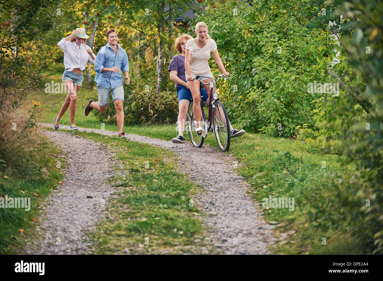 Two young couples chasing each other along dirt track, Gavle, Sweden Stock Photo