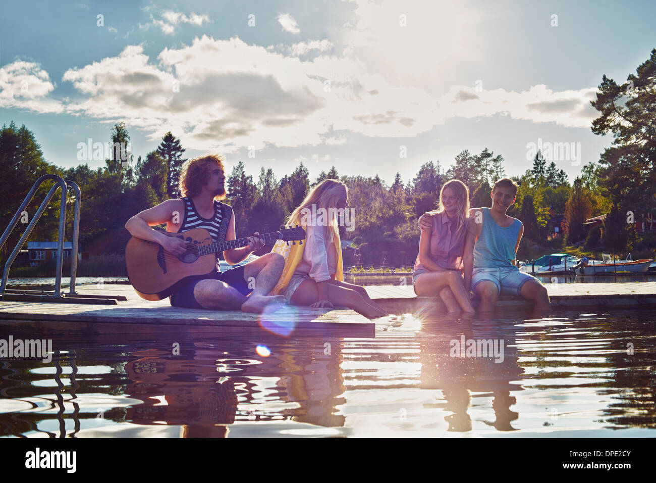 Two young couples relaxing on pier, Gavle, Sweden Stock Photo