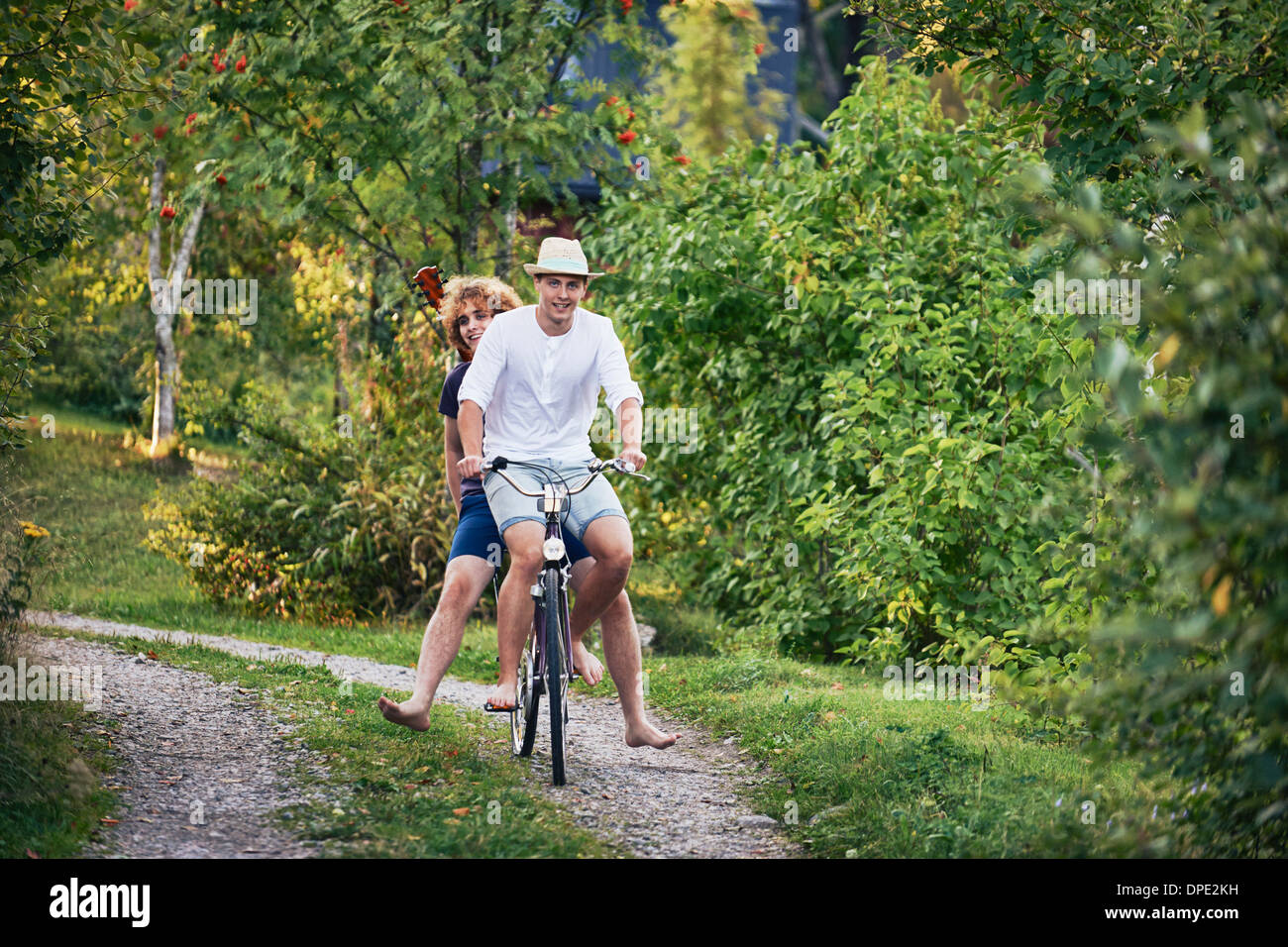 Two young men riding bicycle barefoot, Gavle, Sweden Stock Photo