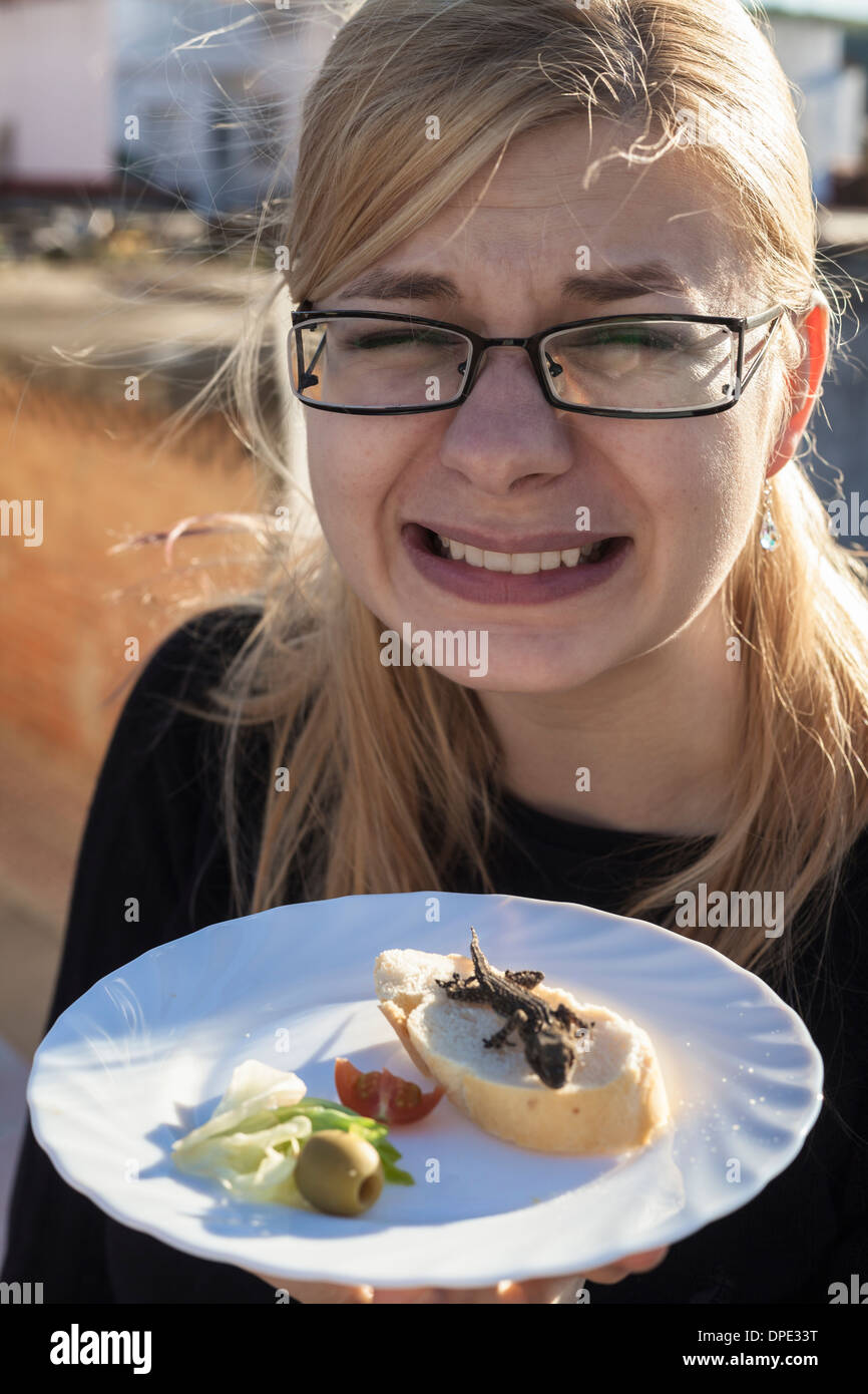 Disgusted woman with lizard on the plate. Stock Photo