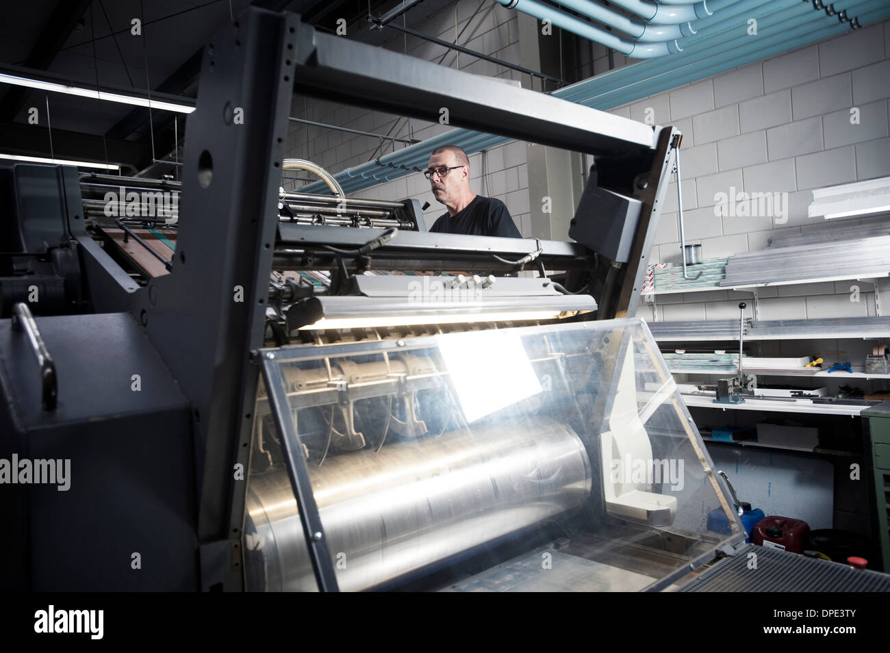 Worker operating printing machine in print workshop Stock Photo