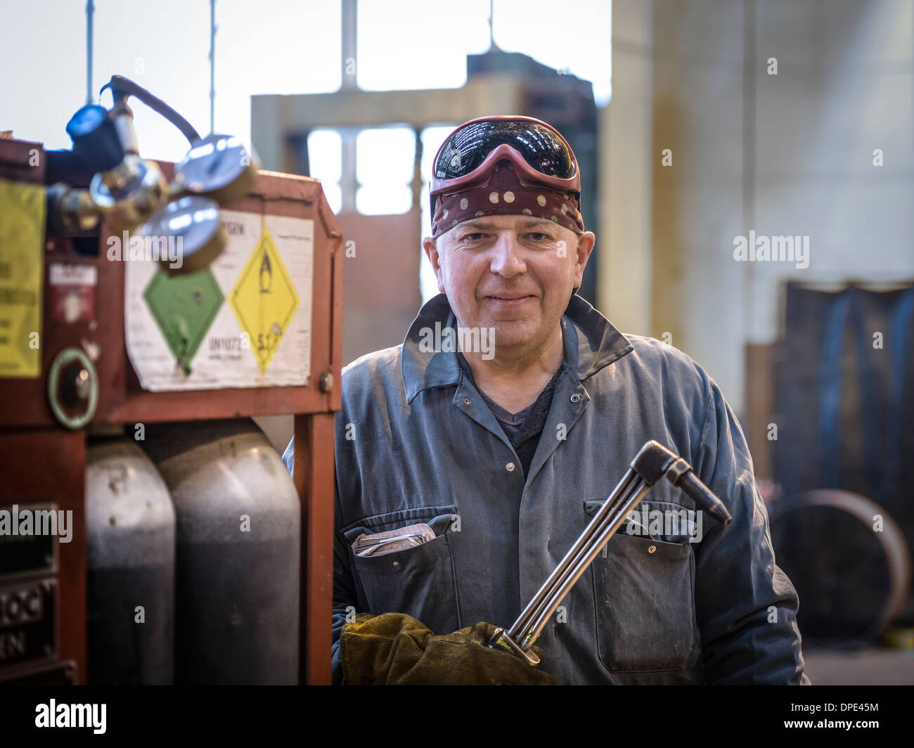 Portrait of welder in overalls and safety goggles in factory Stock Photo