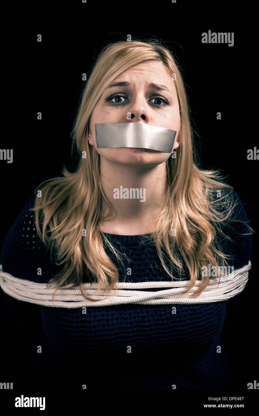 Kidnapped woman hostage with tape over mouth and tied up with rope Stock Photo