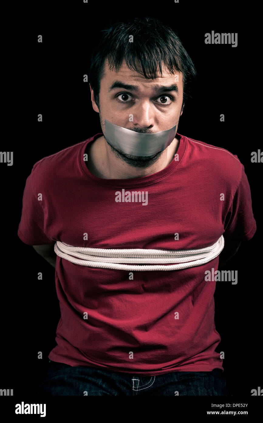 Kidnapped man hostage with tape over mouth and tied up with rope Stock Photo