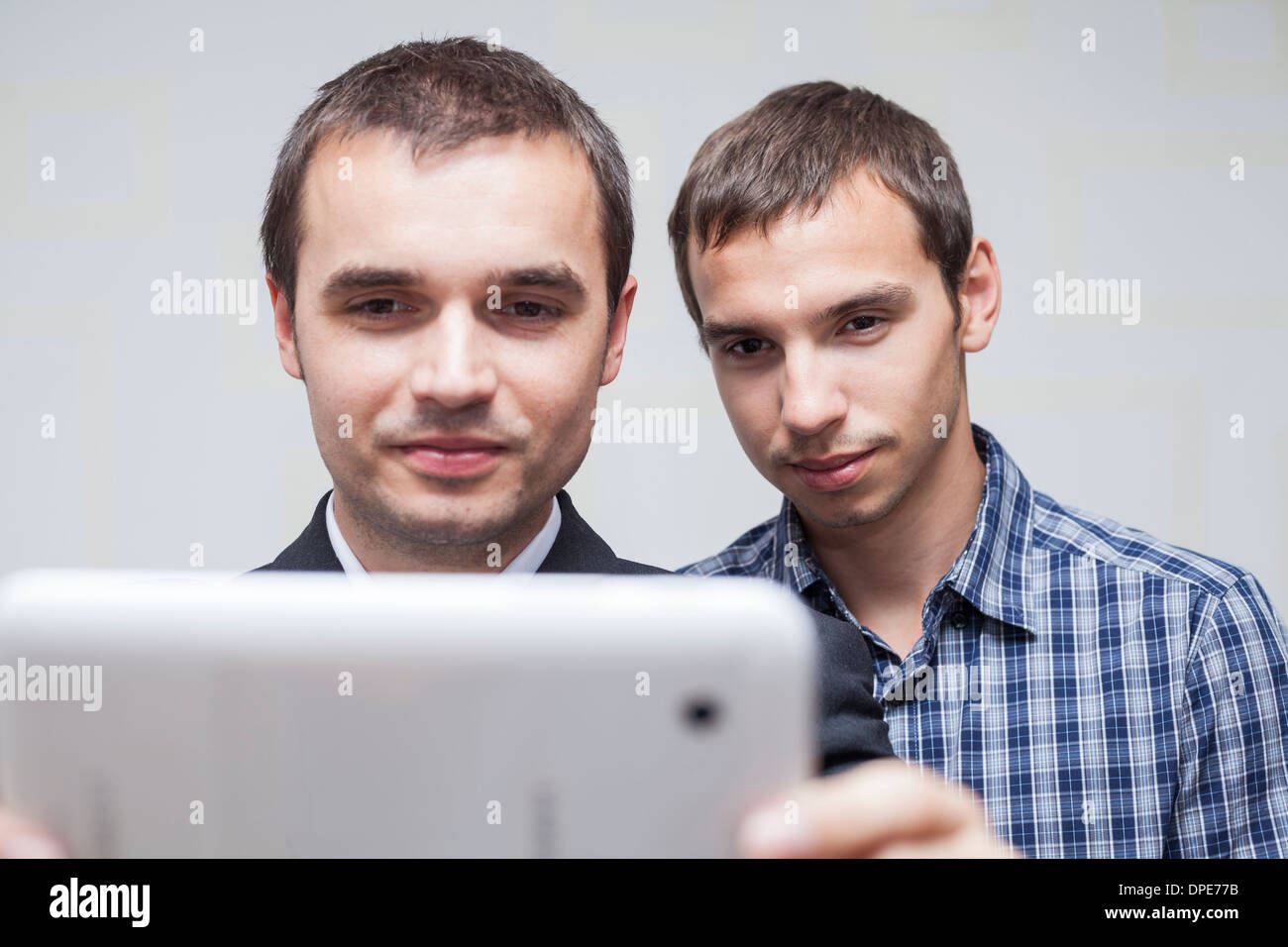 Closeup of two smiling businessmen looking at digital tablet. Stock Photo