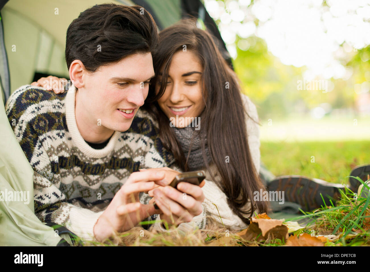 Young couple in tent using smartphone Stock Photo