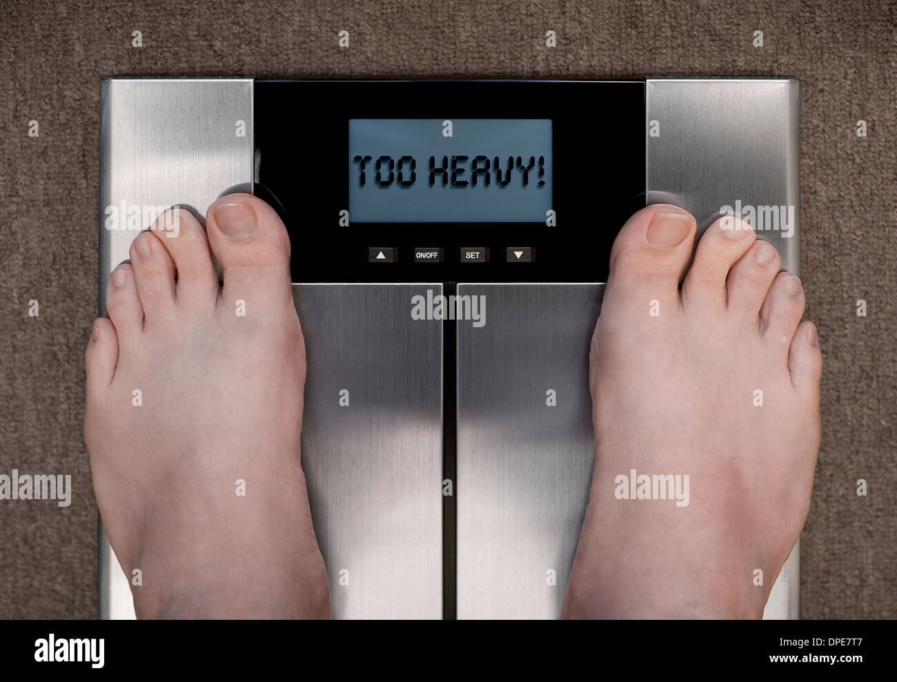 Man's Feet on Bathroom Scales Display Showing TOO HEAVY! Concept Stock Photo