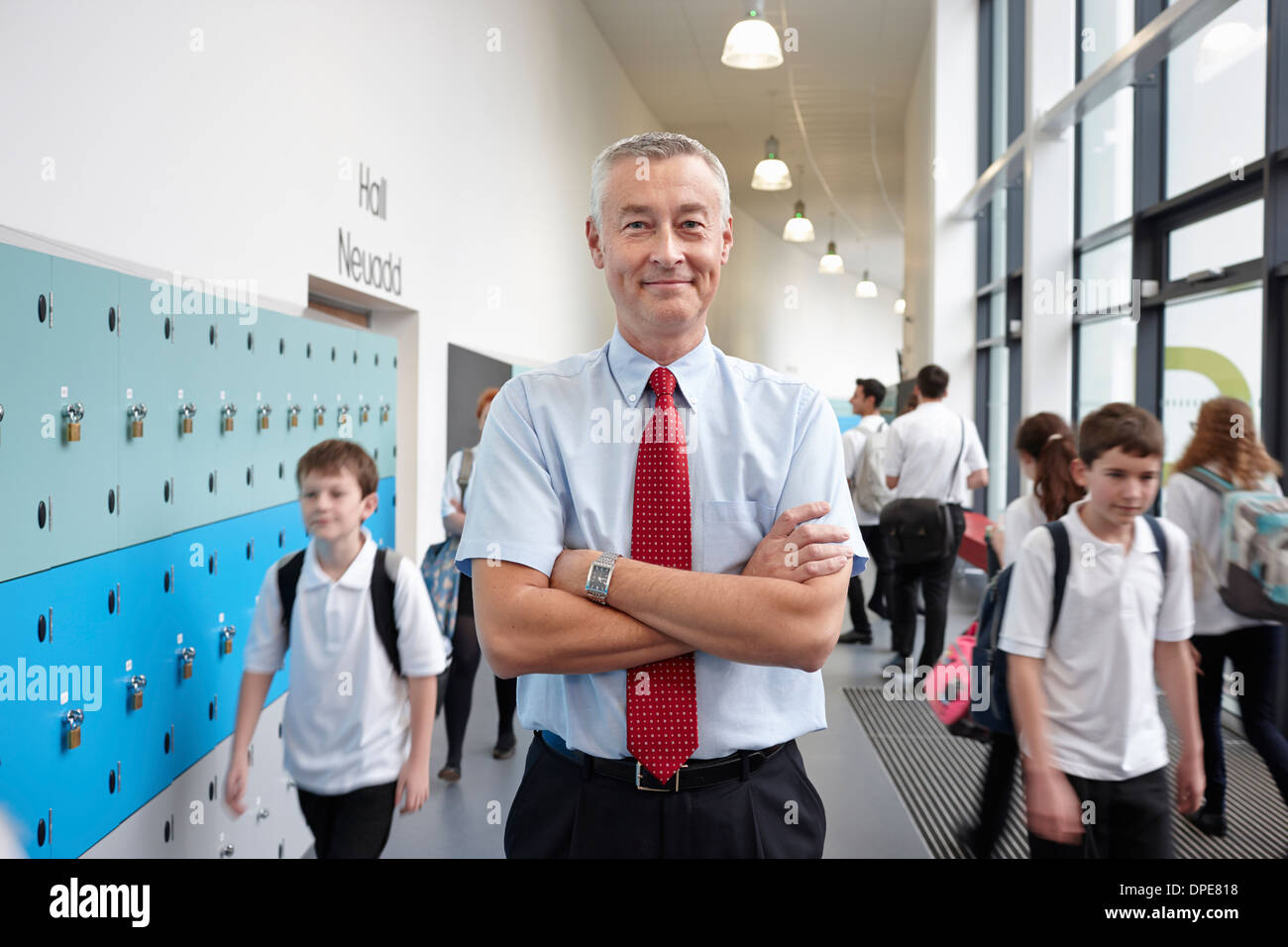 Portrait of male teacher with arms folded in school corridor Stock Photo
