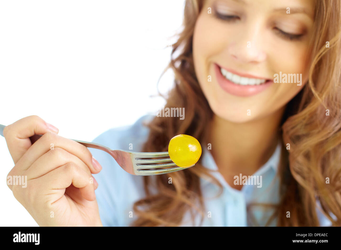 Close-up of frsh cherry tomato on fork held by pretty girl Stock Photo