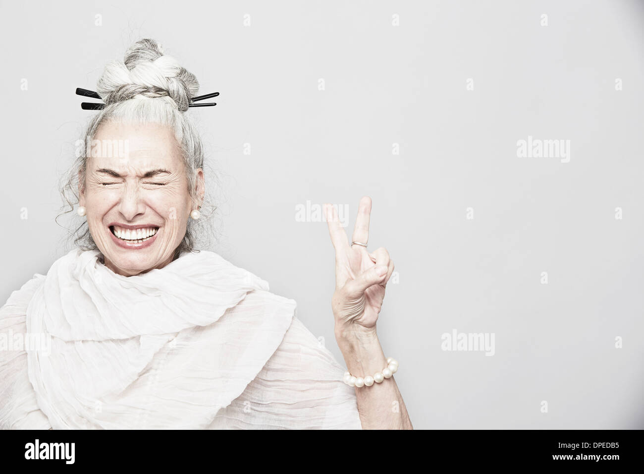 Studio portrait of sophisticated senior woman making victory sign Stock Photo