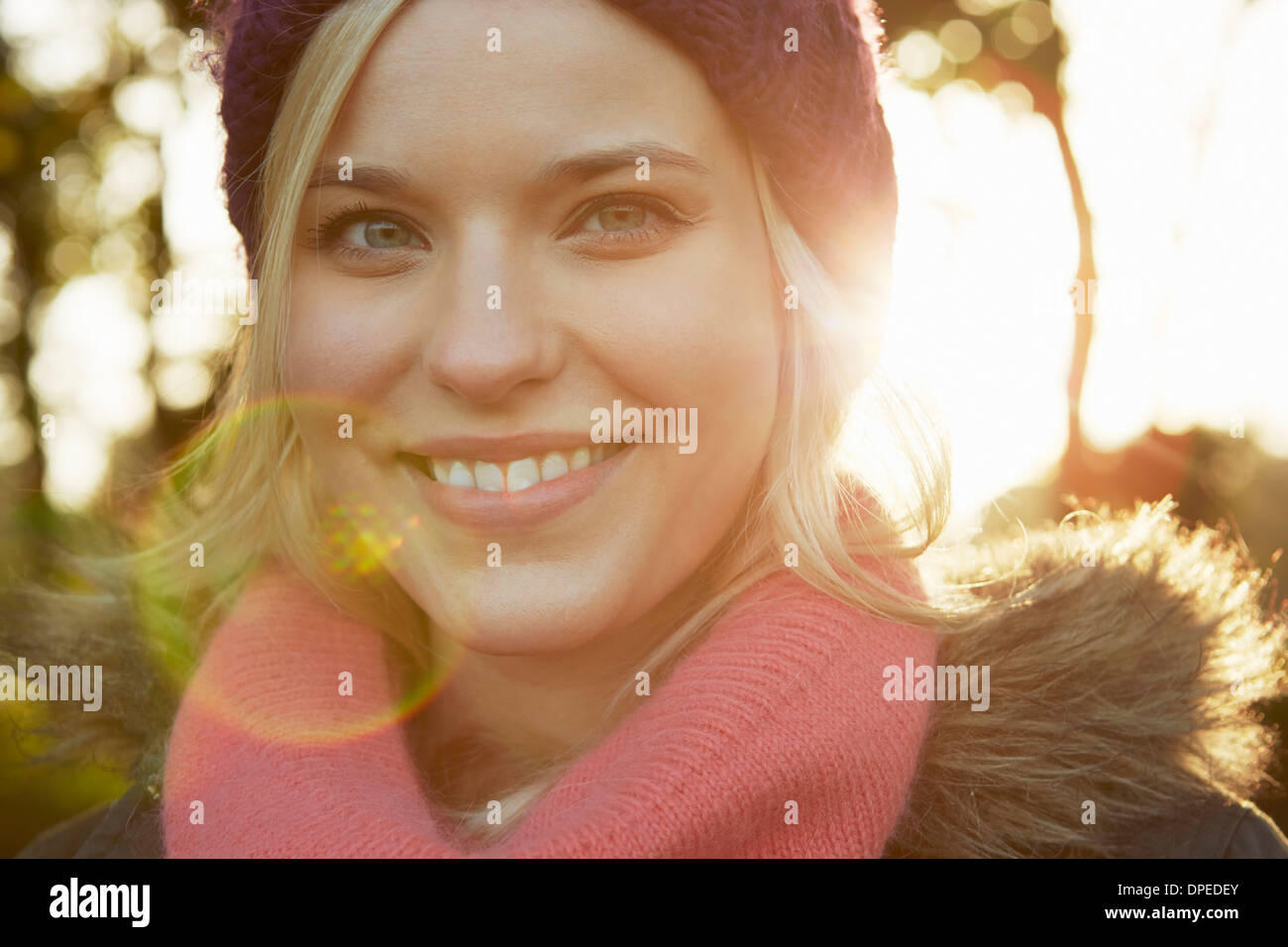 Portrait of young woman in park, wearing knit hat and scarf Stock Photo