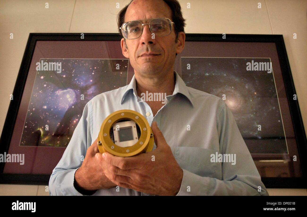 (Published 7/12/2004, B-1, UTS1819030) San Diego State University (SDSU) astronomer Bob Leach  held a 2k X 2k CCD head as stood in front of photos taken using his company's technology, which were displayed on the walls of his Mission Valley office. Stock Photo