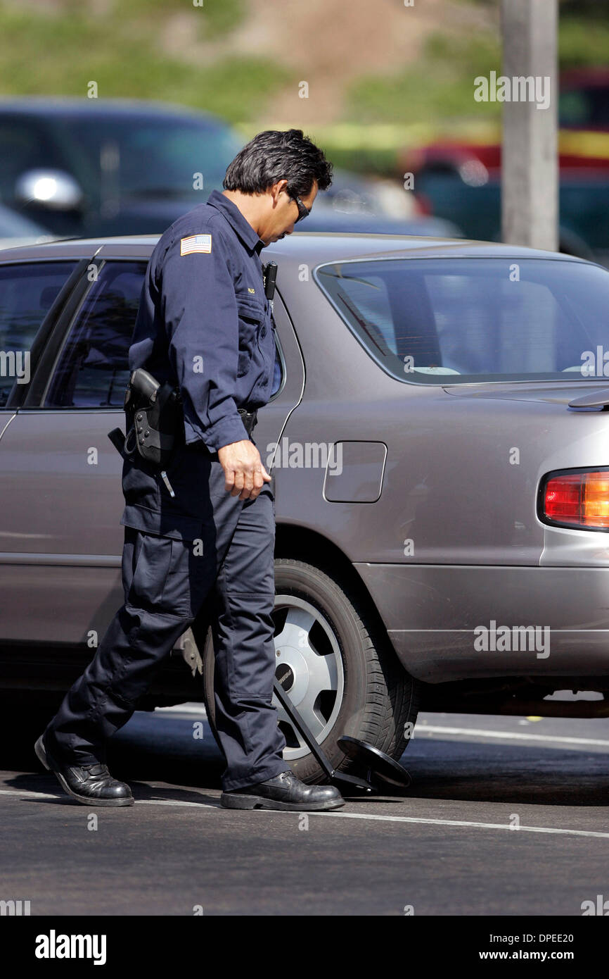 (Published 10/12/2006, B-2:R)  OCTOBER 11, 2006, SAN DIEGO, CALIFORNIA, USA  ................................. Using a mirror a Fire Investigator inspects cars left in the parking of the grocery store on  Murphy Canyon Road where earlier the bank inside the grocery store was robbed.  SDPD PAO reports that the bank robber left a bag behind containing a suspicious, which they then ca Stock Photo