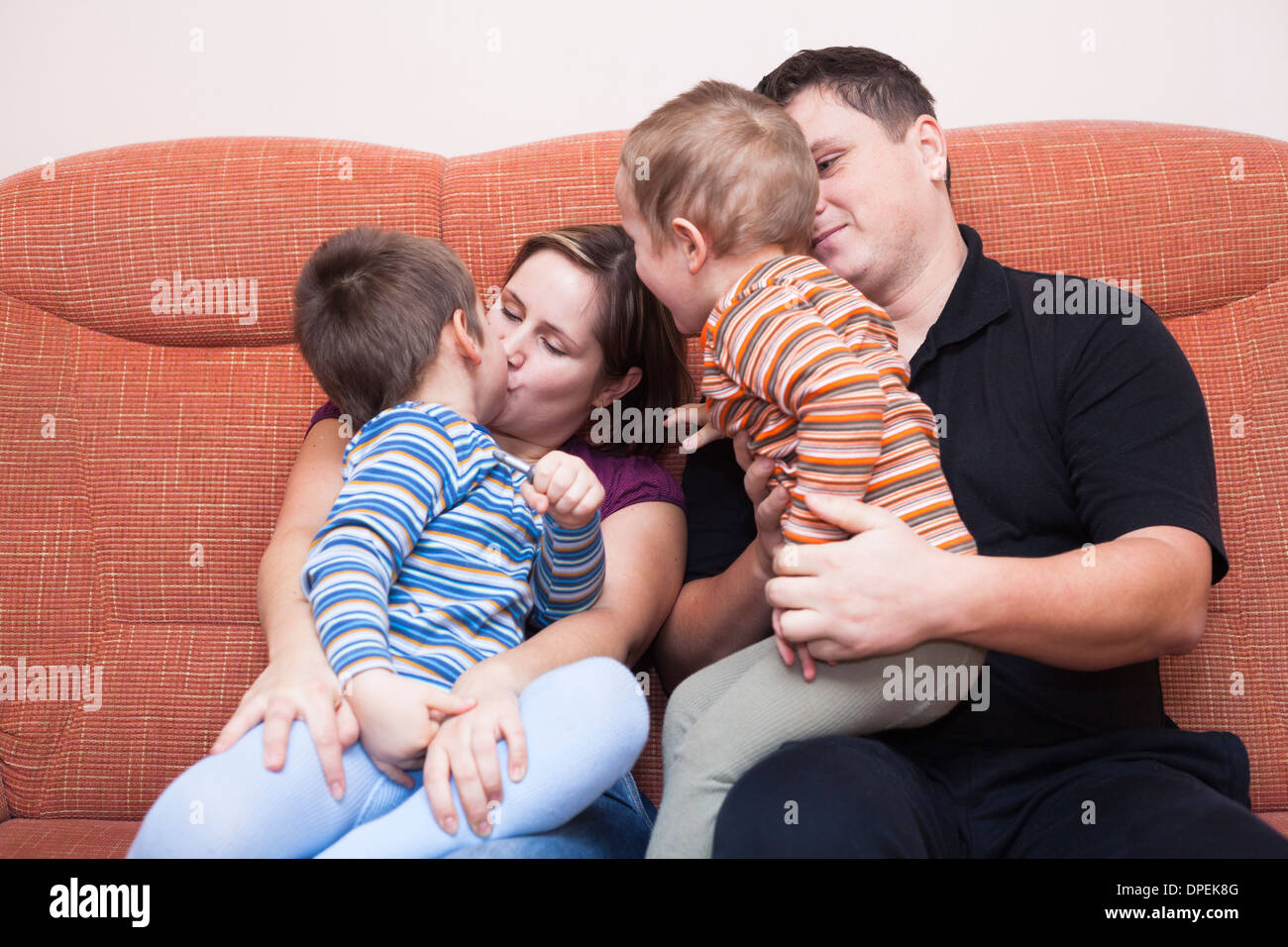 Happy parents kissing with their children at home Stock Photo