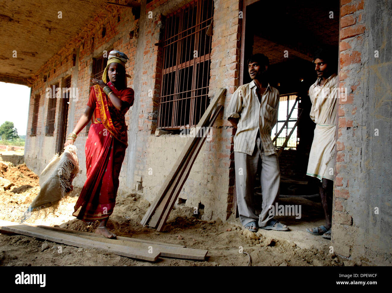 Oct. 04, 2006 - Lucknow, UTTAR PRADESH, INDIA - In a village outside of Lucknow, India, a woman of a lower caste works on the construction site of a new school under the watchful gaze of her male fellow workers. (Credit Image: © Mary F. Calvert/ZUMApress.com) Stock Photo