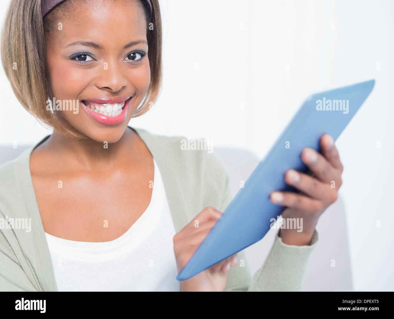 Happy elegant woman sitting on sofa using her tablet Stock Photo - Alamy