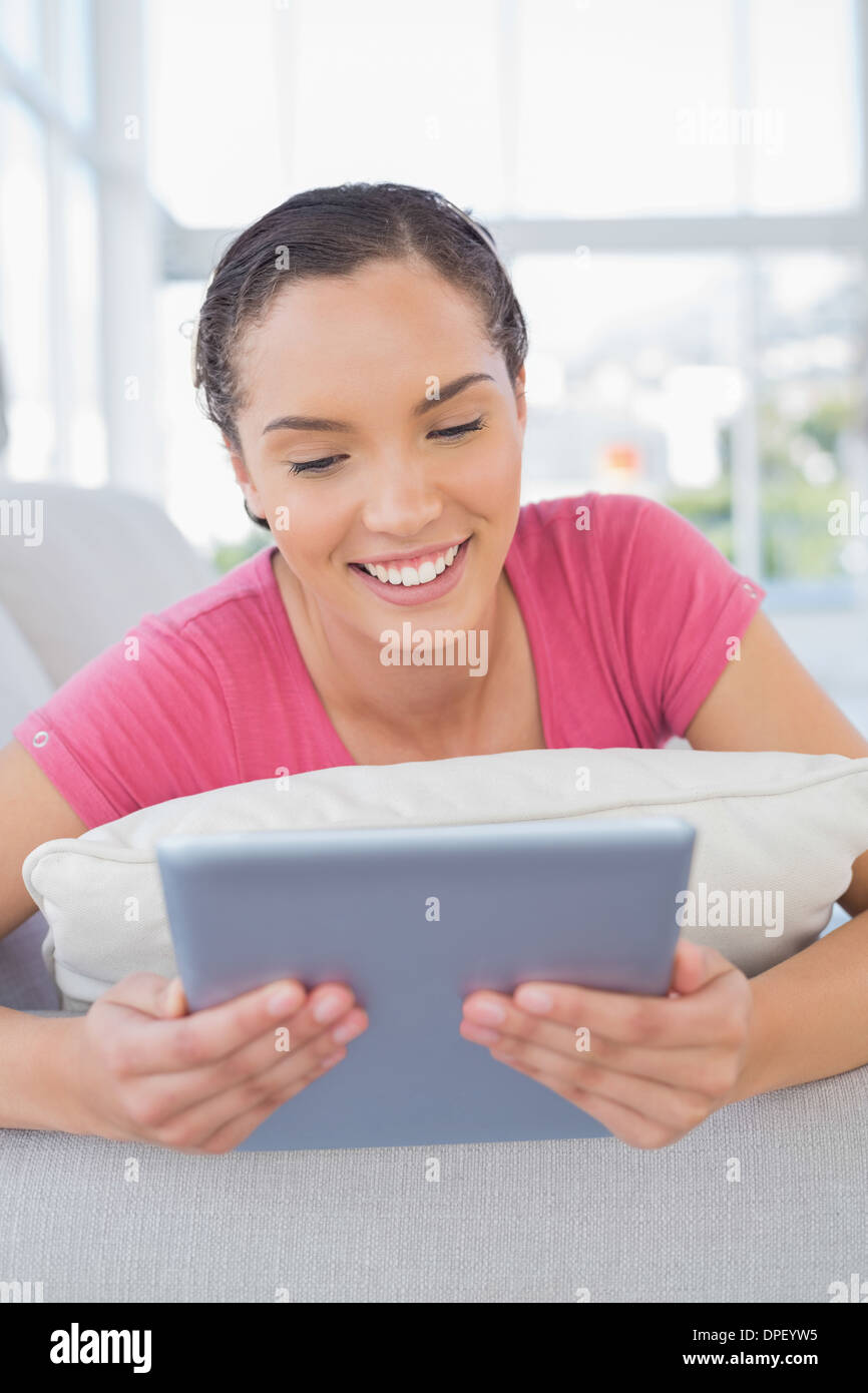Happy woman lying on sofa and using tablet Stock Photo - Alamy