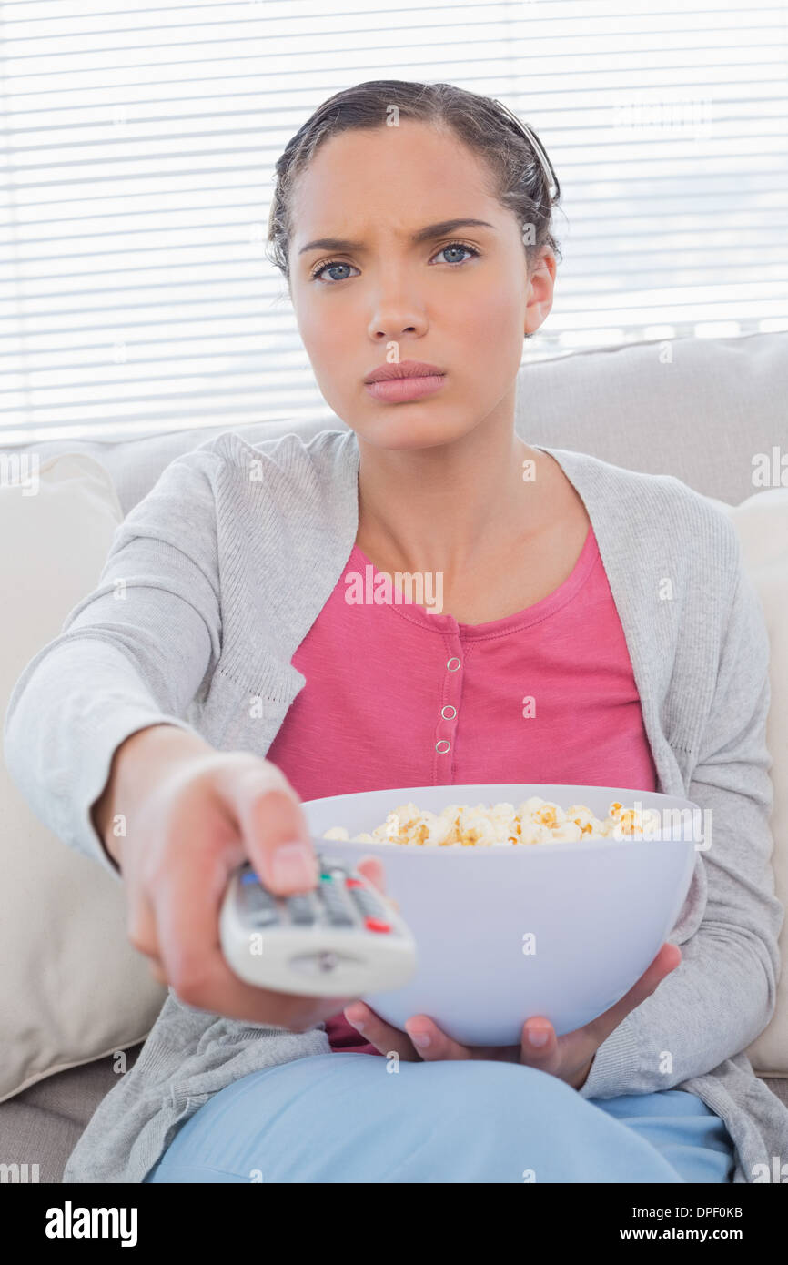 Serious woman eating popcorn while watching tv Stock Photo Alamy