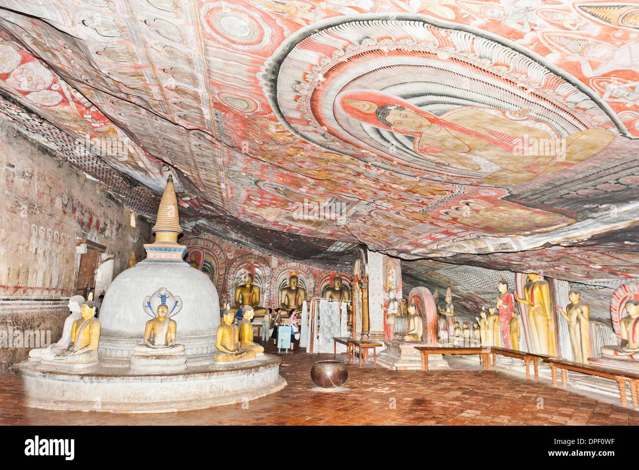 Fully painted interior room of the cave, colourful murals on the walls and the ceiling, frescoes, statues and a stupa Stock Photo
