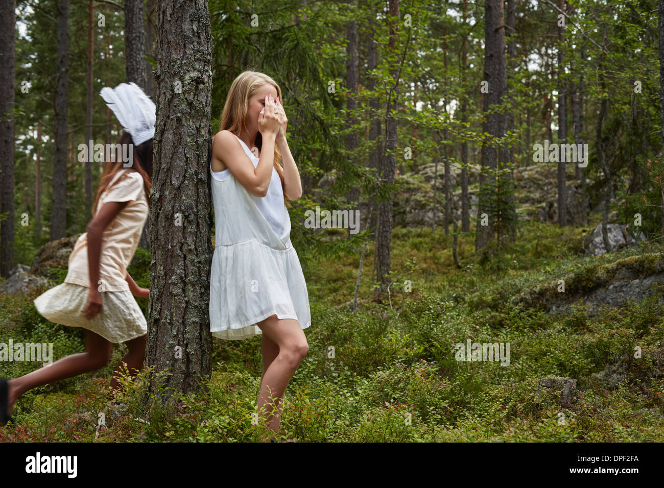 Teenage girls playing hide and seek in forest Stock Photo