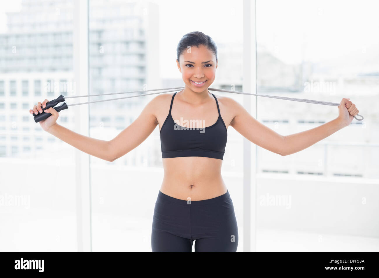 Pretty dark haired model in sportswear holding a skipping rope Stock Photo