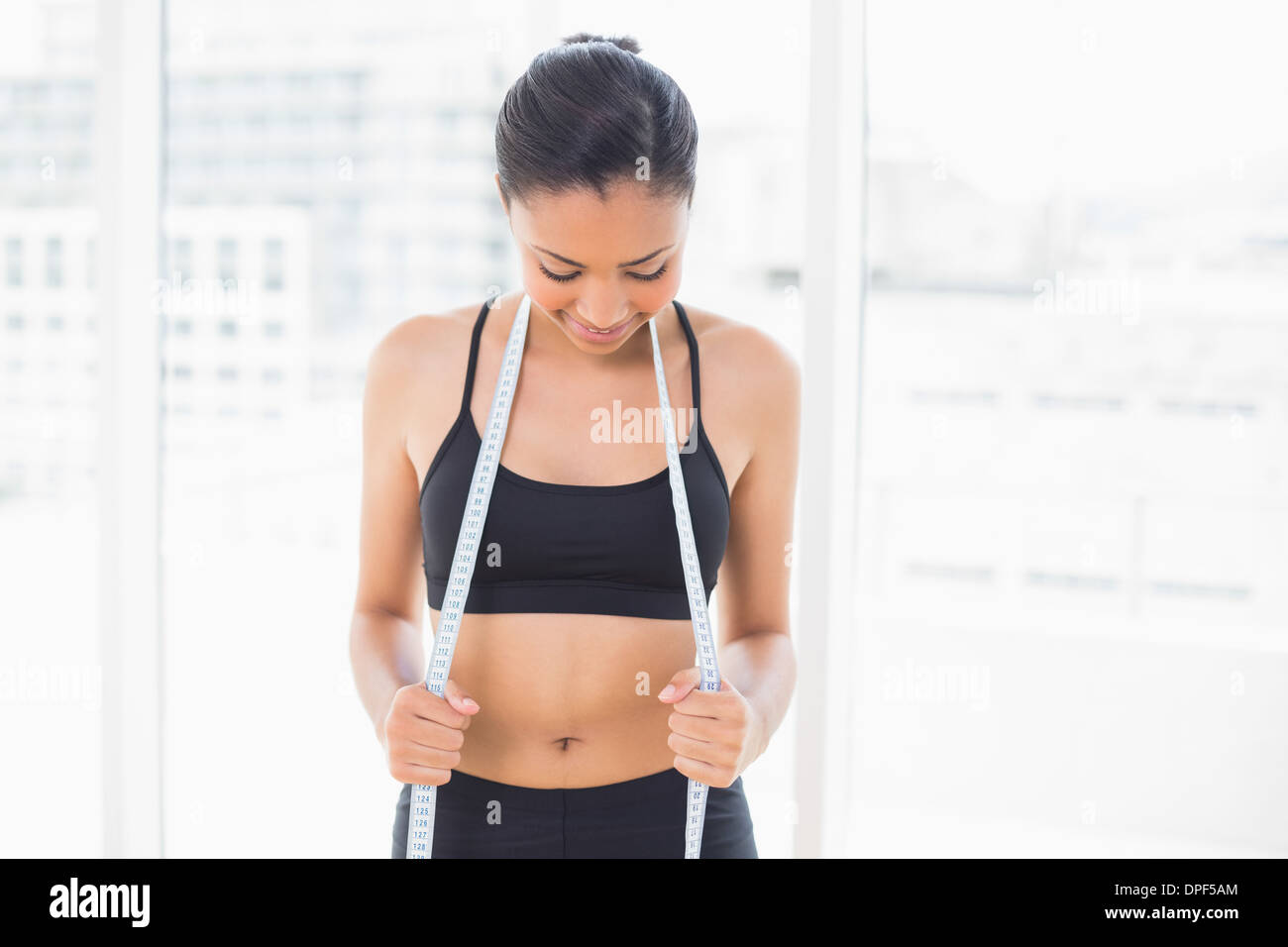Beautiful dark haired model in sportswear holding a measuring tape Stock Photo