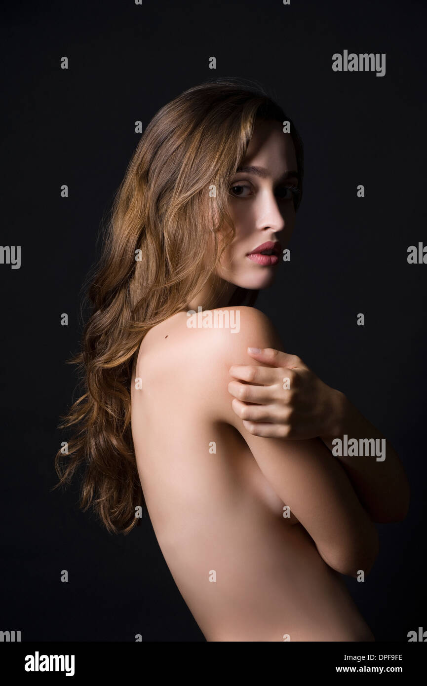 Studio portrait of sultry young woman with arms folded Stock Photo