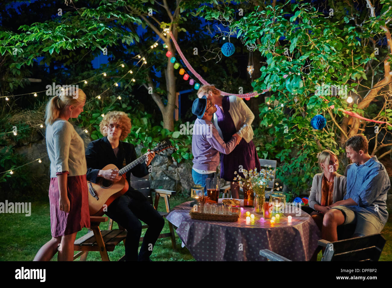 Three couples enjoying evening garden party Stock Photo