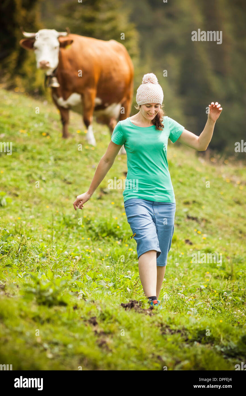 Woman walking through cows' field Stock Photo