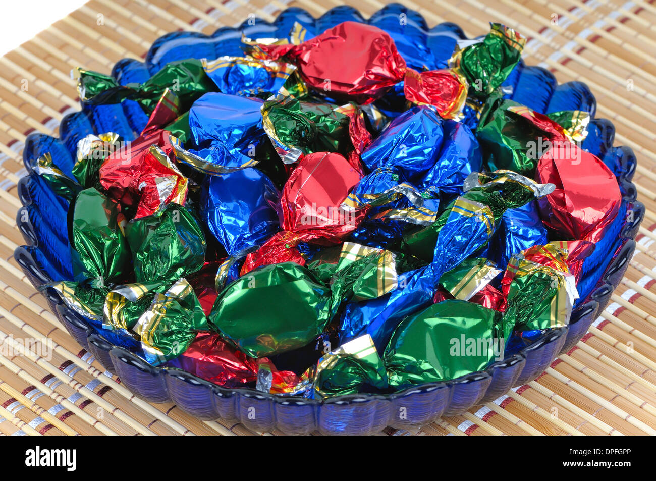 Chocolate candy with wrappers of different colors in the glass blue dish Stock Photo