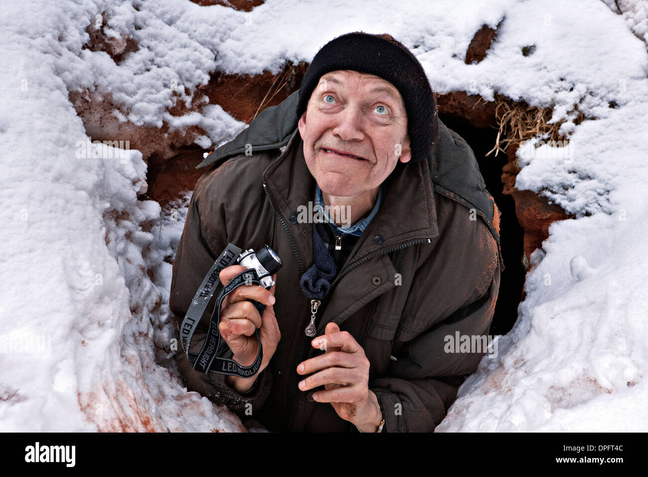 Elderly man takes every effort to get out of the Liivian offering cave at Svetupe river Latvia Stock Photo