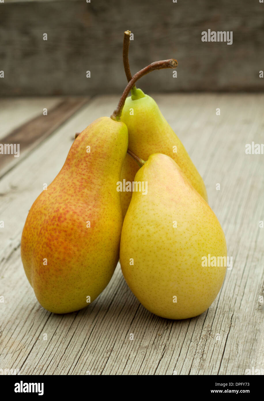 Three ripe pears with cuttings on a wooden background Stock Photo