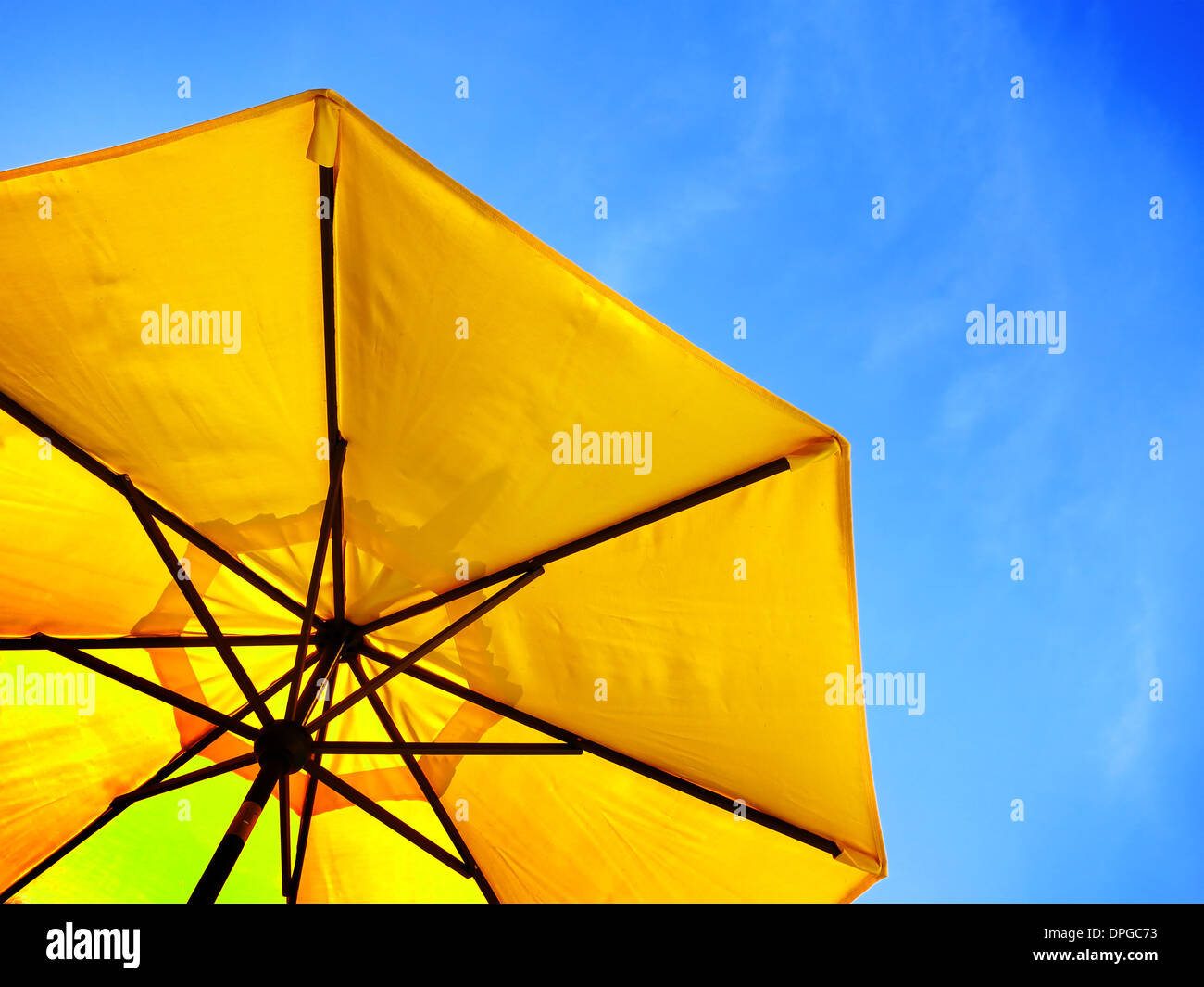 Yellow umbrella and blue sky symbolizing vacationing in summer Stock Photo