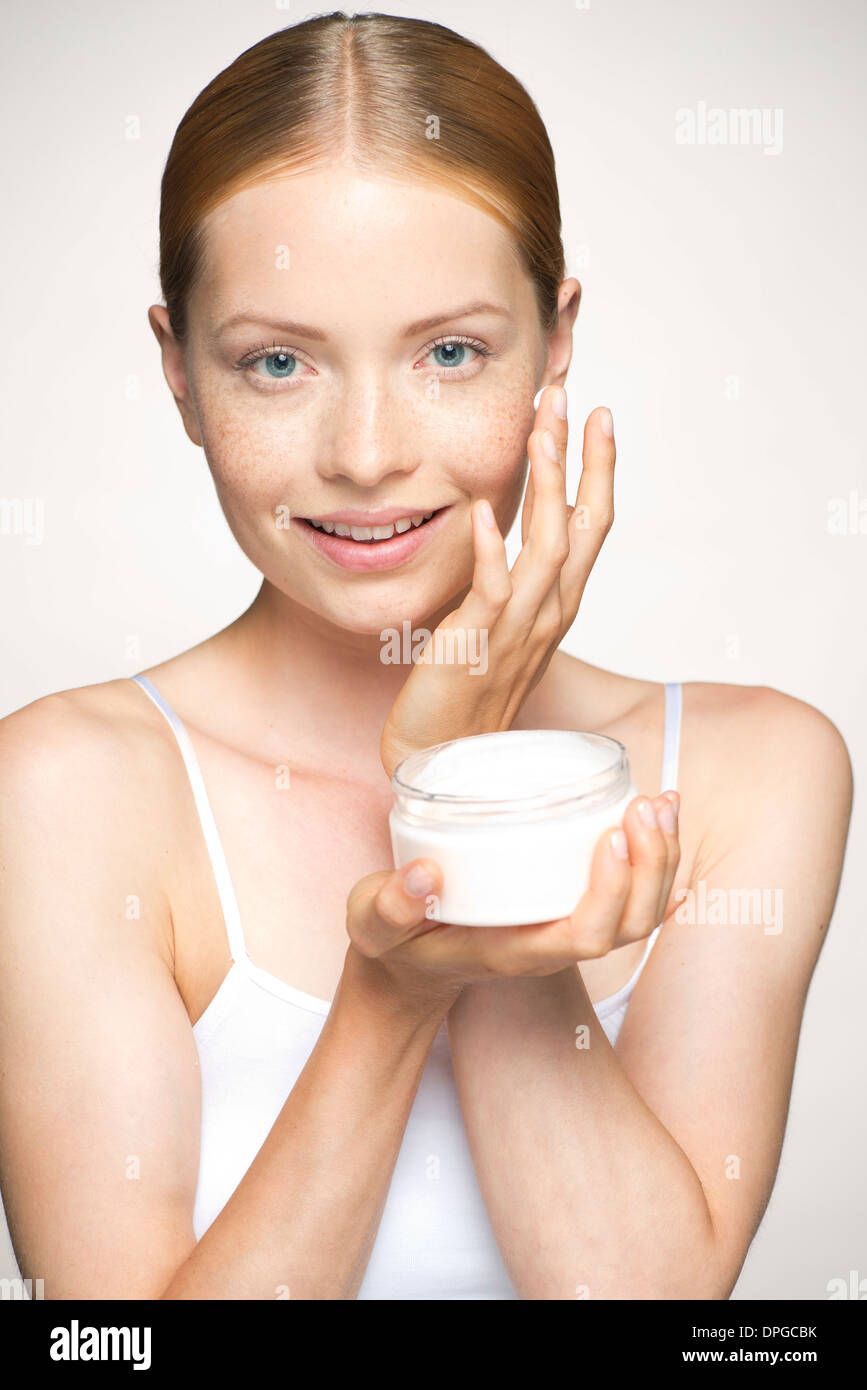 Young woman moisturizing face Stock Photo