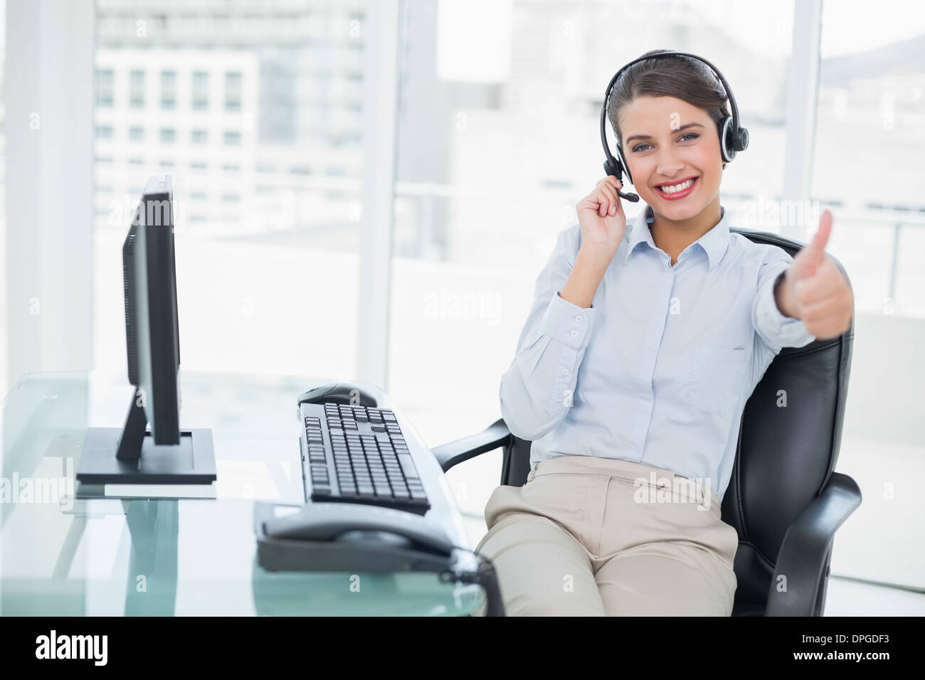 Cheering classy classy brown haired operator raising her thumb Stock Photo