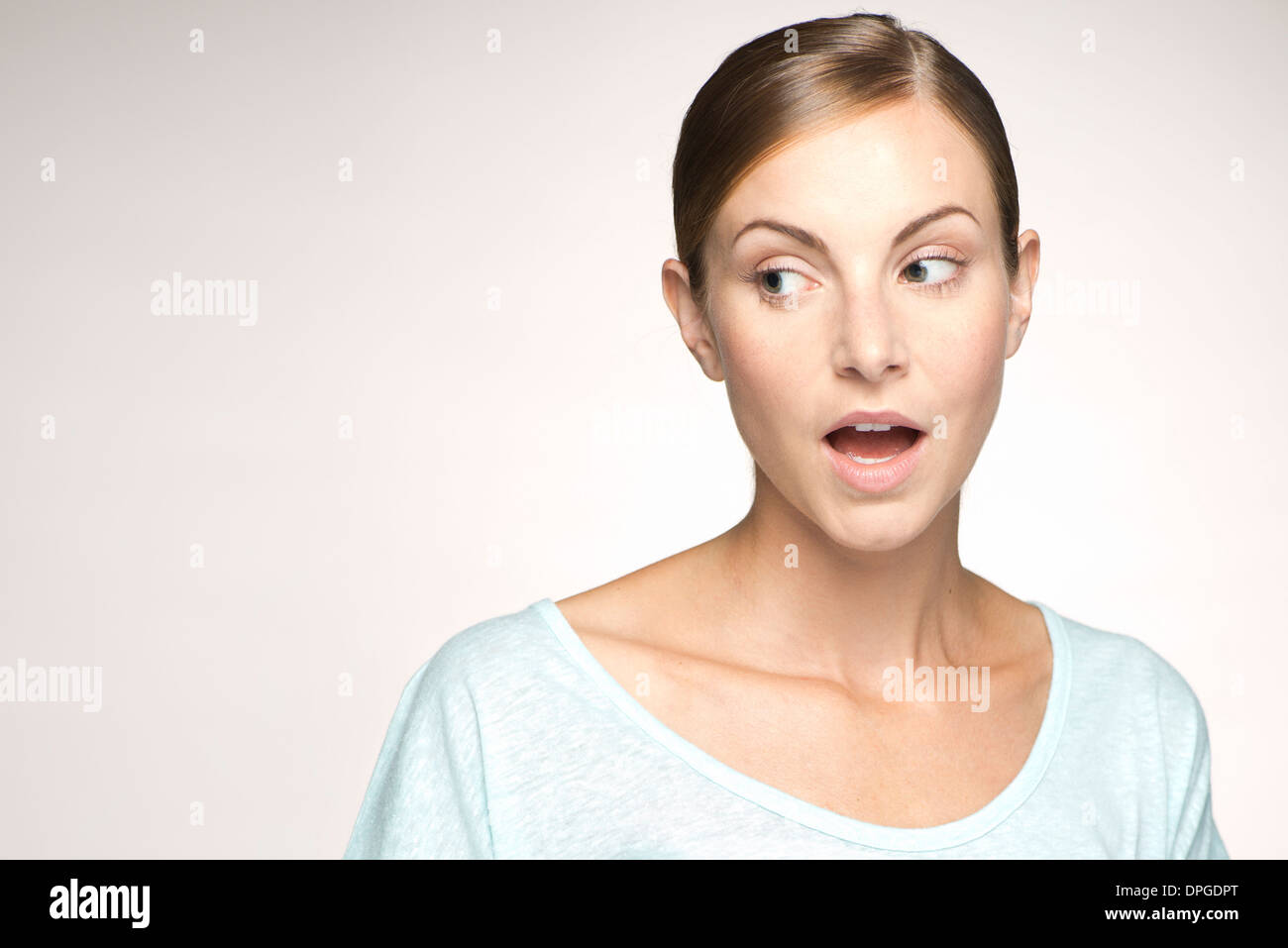 Young woman looking away with mouth open in surprise, portrait Stock Photo