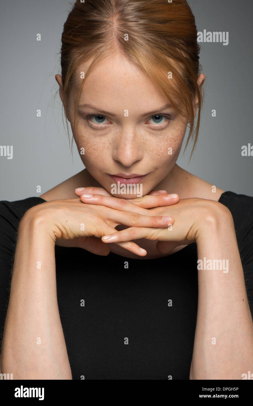 Young woman resting chin on hands, looking seductively at camera Stock Photo