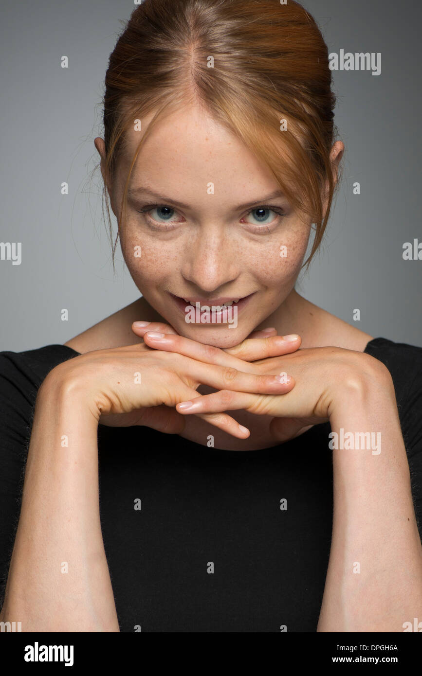 Young woman resting chin on hands, smiling, portrait Stock Photo