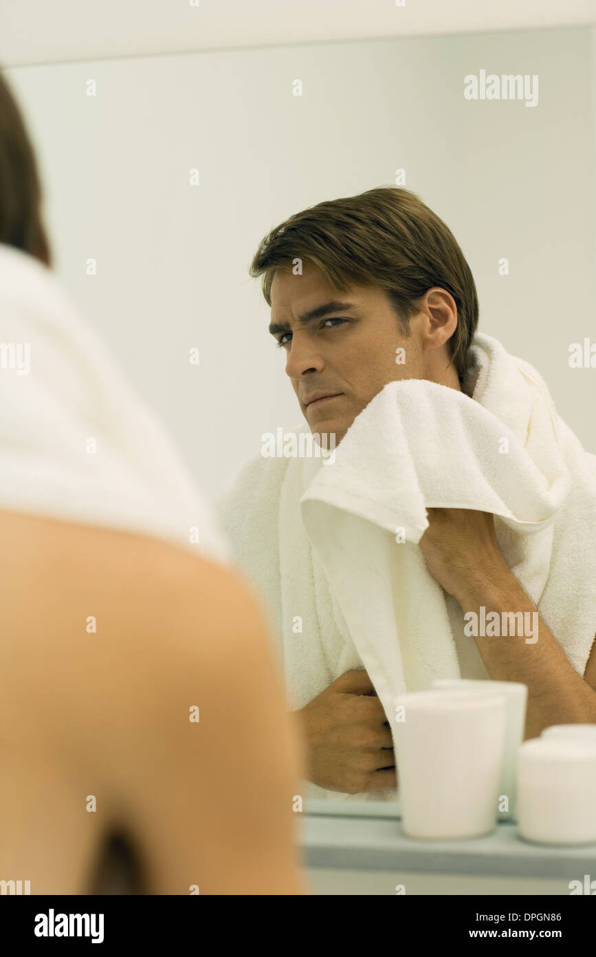 Man looking in mirror, drying face with towel Stock Photo