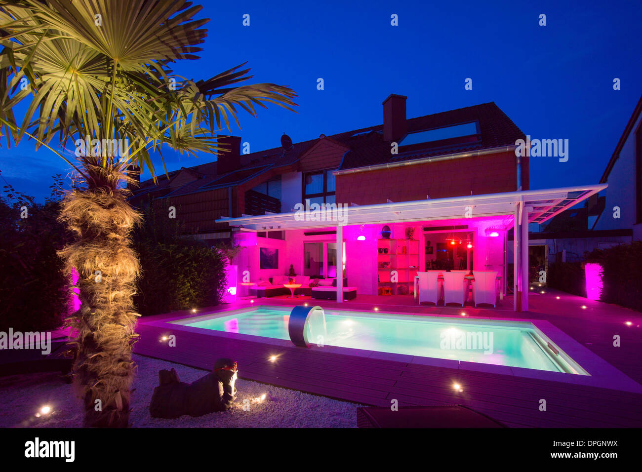 Private terraced house with garden, winter garden, pool, terrace and palm with show lighting at night in summer, Germany, Europe - August 2013 Stock Photo