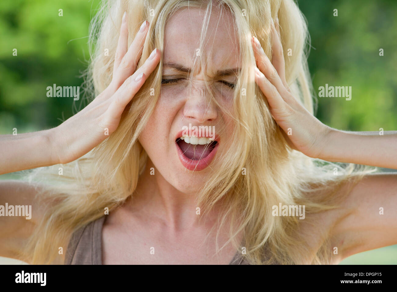 Woman with head in hands, screaming Stock Photo