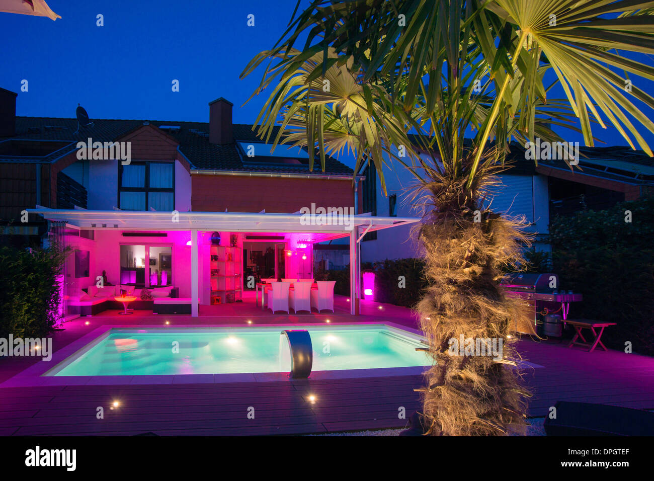 Private terraced house with garden, winter garden, pool, terrace and palm with show lighting at night in summer, Germany, Europe - August 2013 Stock Photo
