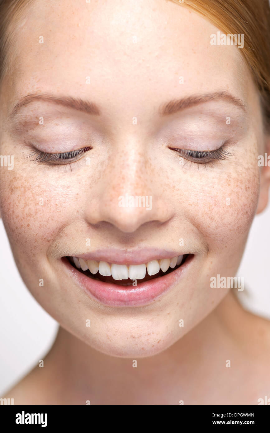 Young woman looking down, smiling, close-up portrait Stock Photo