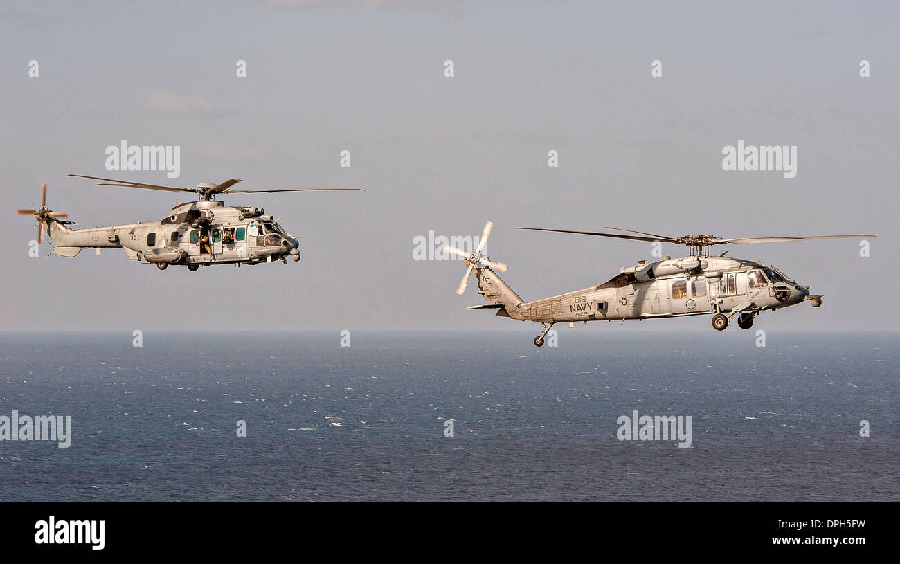 A US Navy MH-60S Sea Hawk flies with a French Air Forces Caracal helicopter during a combat search and rescue training exercise December 31, 2013 in the Gulf of Oman. Stock Photo