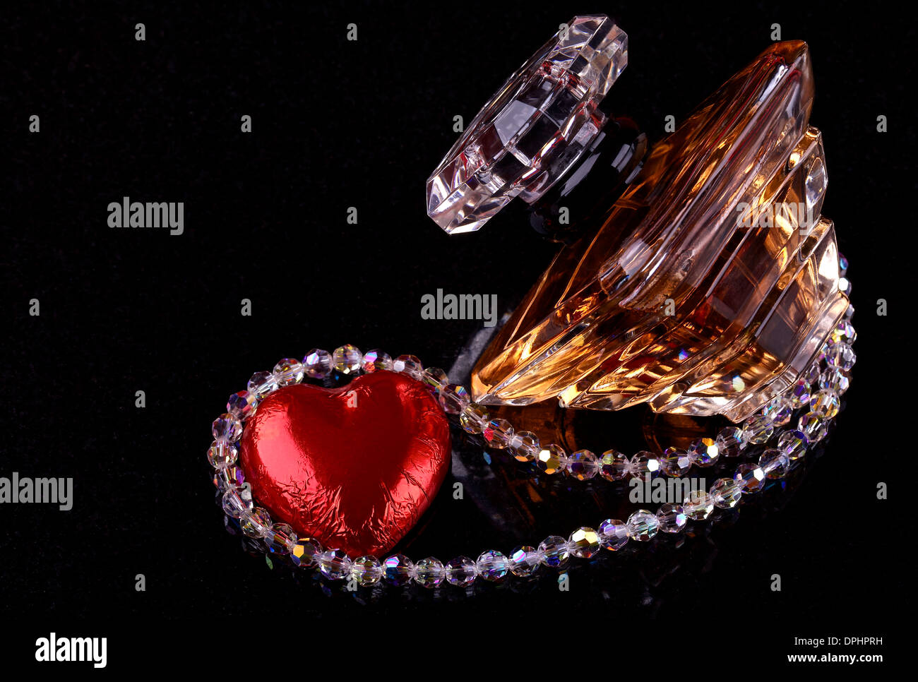 Bottle of perfume jewelry and red heart on black background Stock Photo