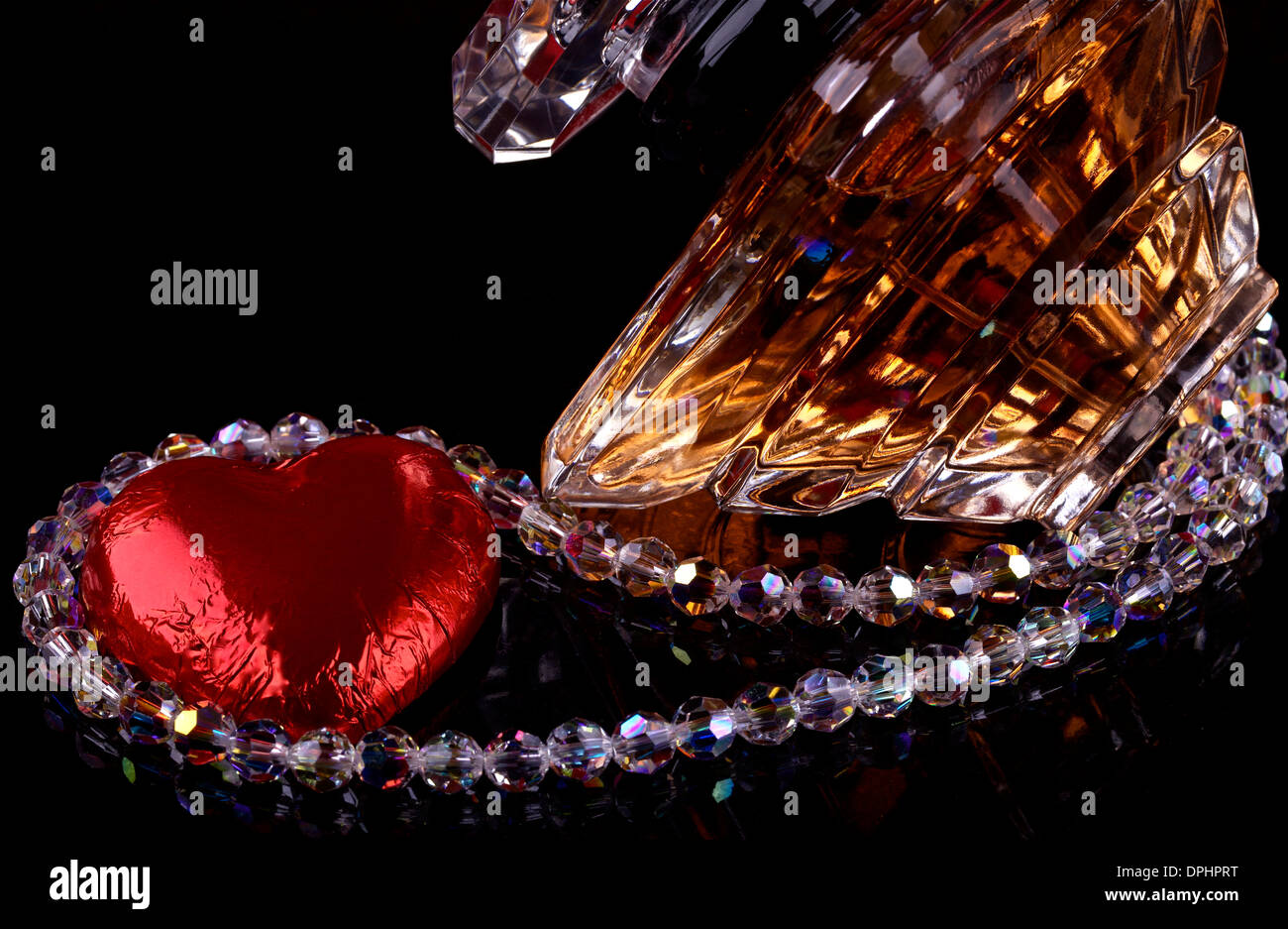 Bottle of perfume,jewelry and red heart on black background Stock Photo