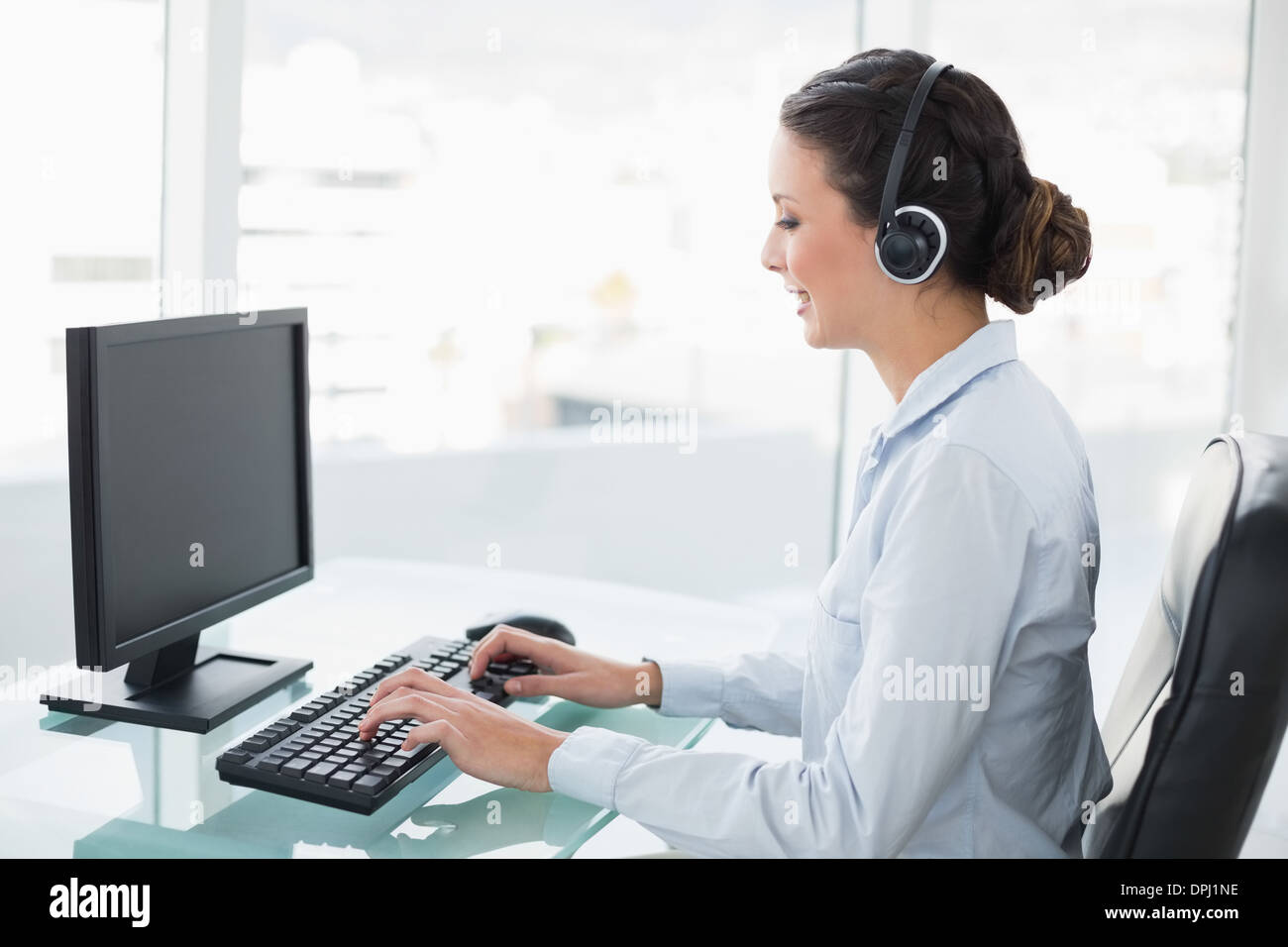 Smiling stylish brunette operator using a computer Stock Photo