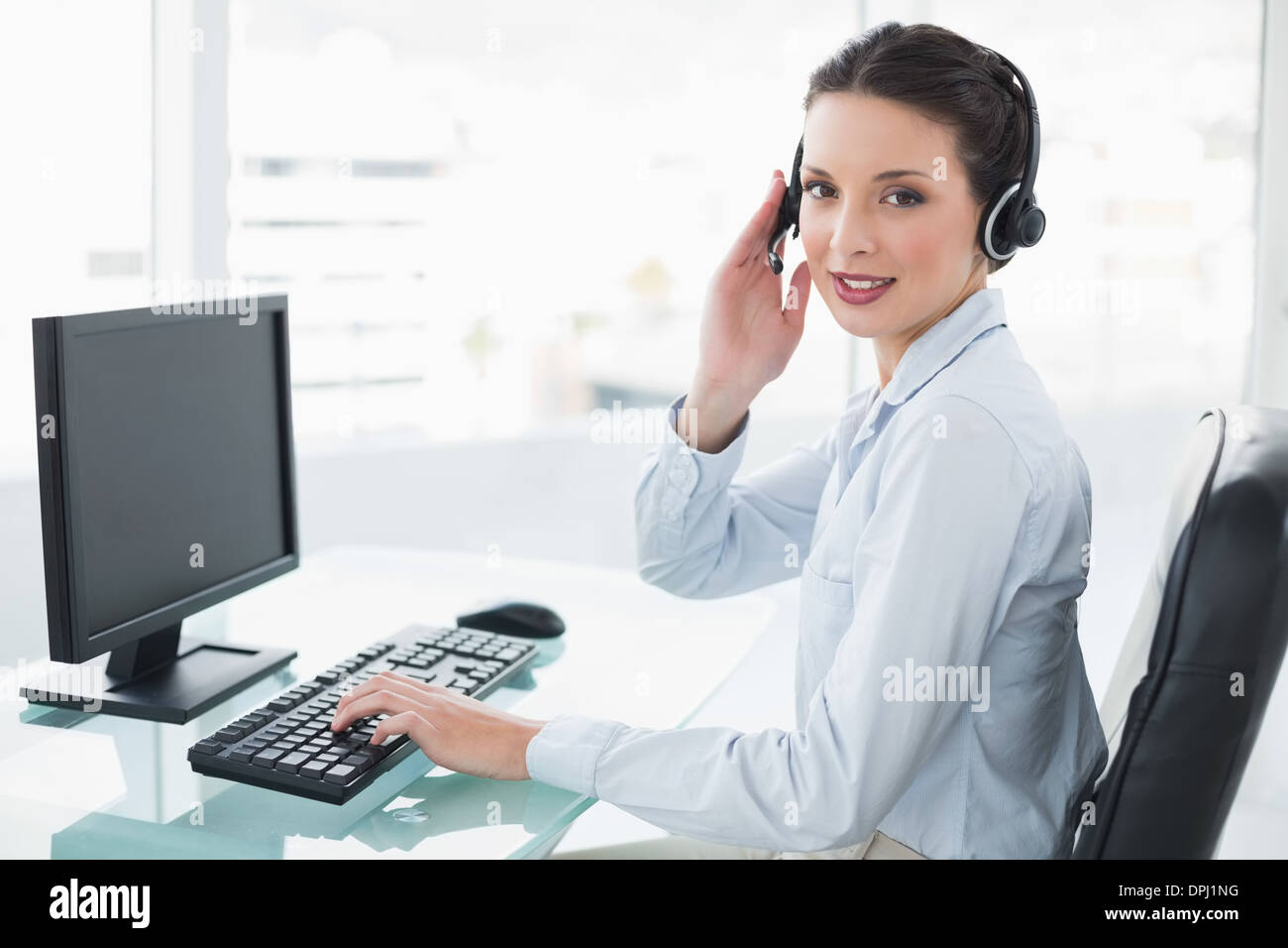 Pretty stylish brunette operator using a computer and answering a call Stock Photo