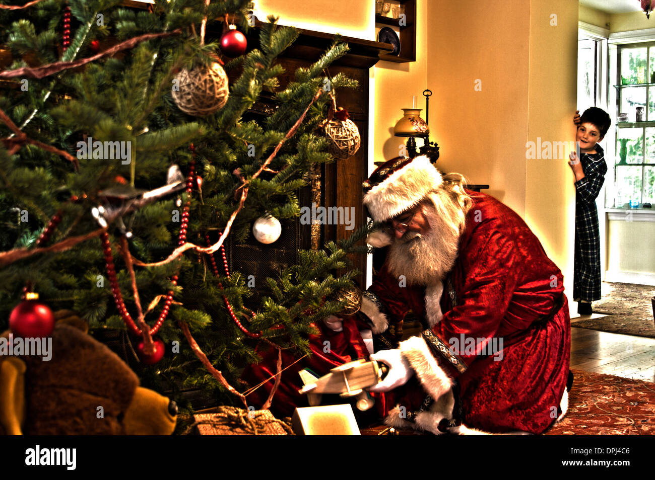 A little boy seeing Santa Claus putting presents under the Christmas