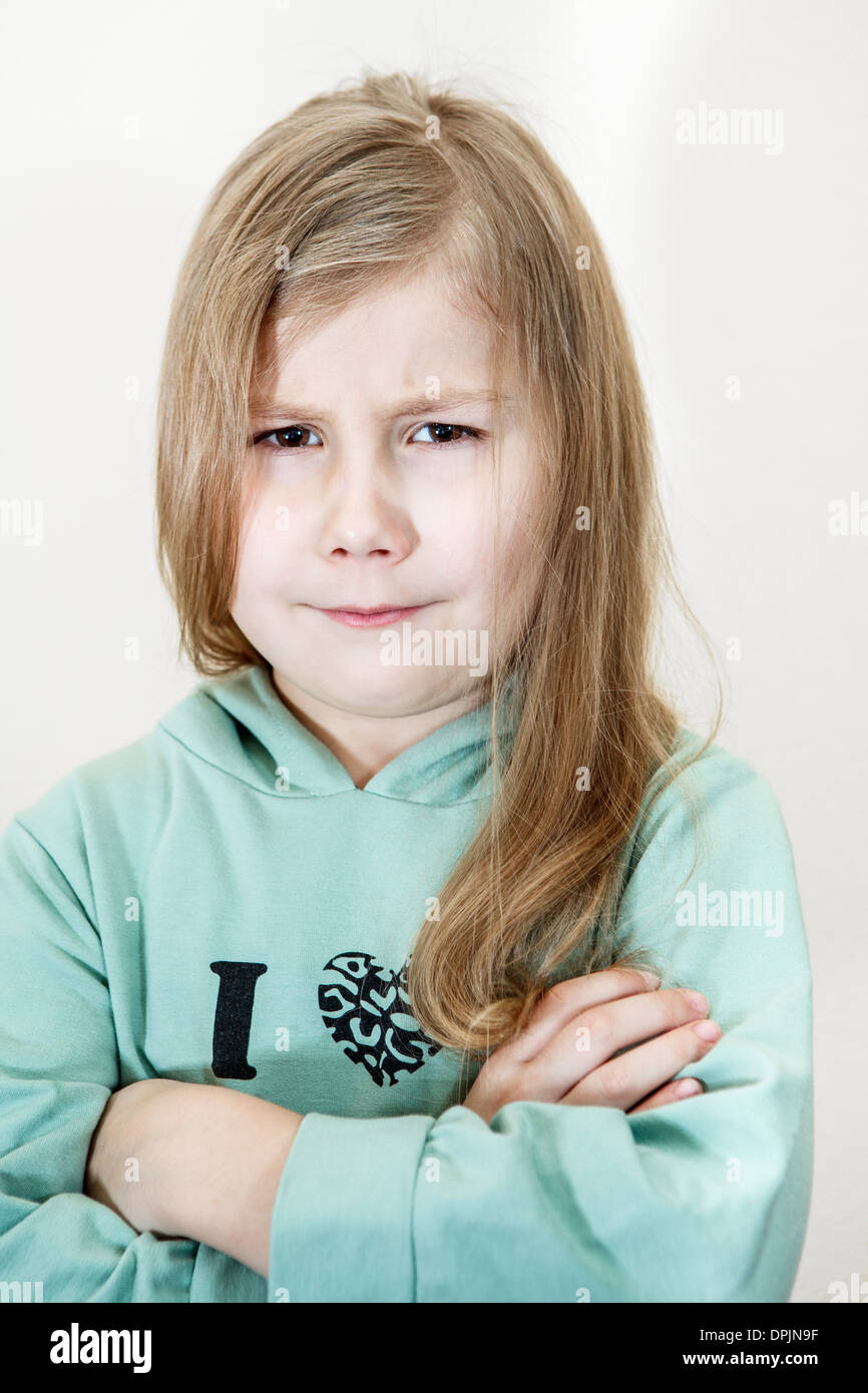 Young girl with an angry look and crossed arms. Head and shoulders portrait Stock Photo